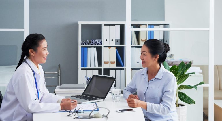Consulting patient Smiling Asian doctor consulting senior female patient