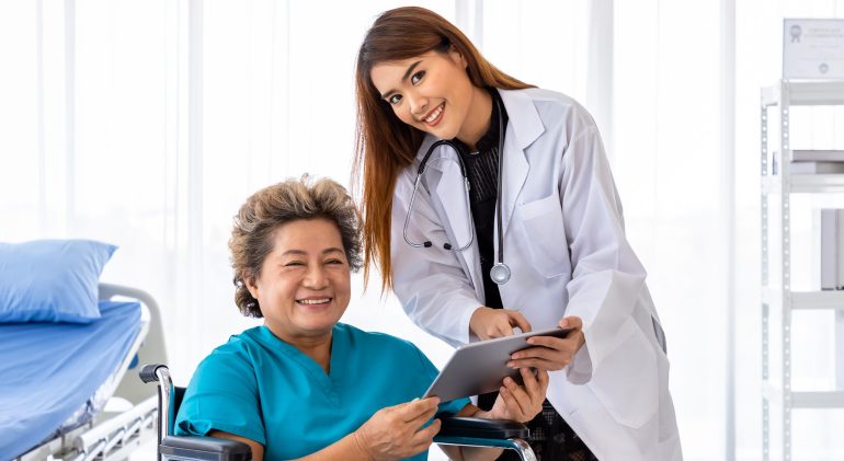 Asian medical doctor take care and explain senior elderly woman Asian medical doctor take care and explain senior elderly woman female patient on wheelchair with tablet, looking at camera