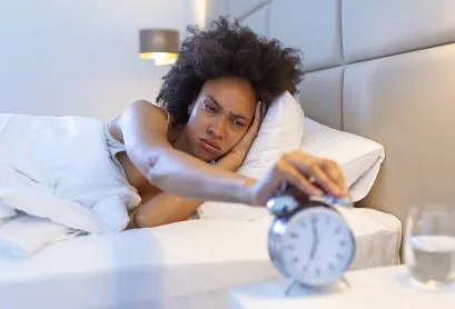 Wake up of an asleep girl stopping alarm clock on the bed in the morning. woman sleeping and wake up to turn off the alarm clock in the morning