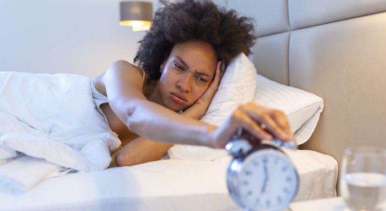 Wake up of an asleep girl stopping alarm clock on the bed in the morning. woman sleeping and wake up to turn off the alarm clock in the morning Wake up of an asleep girl stopping alarm clock on the bed in the morning. woman sleeping and wake up to turn off the alarm clock in the morning